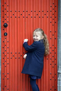 Woman standing against red door