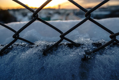 Close-up of snow covered metal against sky