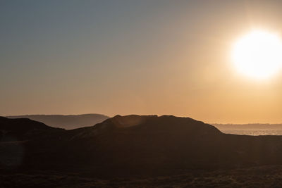 Scenic view of silhouette mountains against clear sky during sunset
