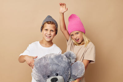 Portrait of smiling sibling against beige background