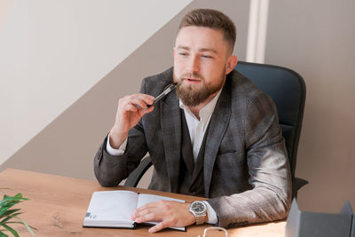 Businessman writing notes while sitting at his desk. young bearded man