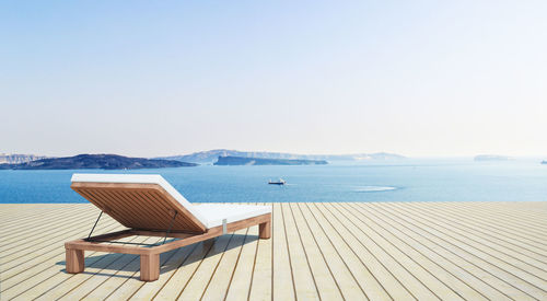 Chaise longue by sea against sky