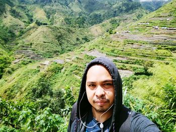 Portrait of young man against green mountains