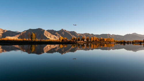 Scenic view of lake by mountains against clear blue sky