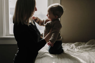 Mother playing with son in bedroom at home