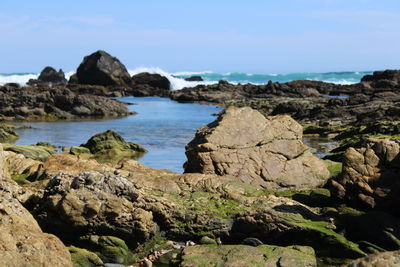 Scenic view of rocks on shore, waves breaking in the background 