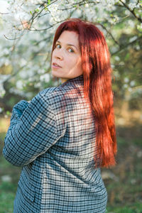 Young woman standing against trees