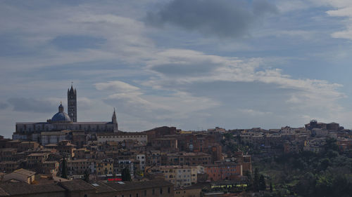 Buildings in city against cloudy sky