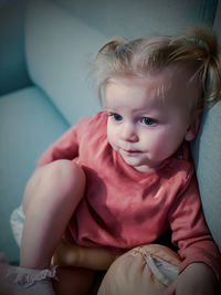 Portrait of cute girl sitting on sofa at home