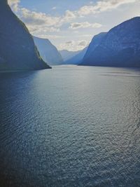 Scenic view of sea by mountains against sky