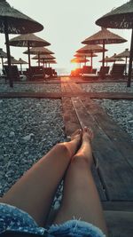 Low section of woman sitting on beach against sky