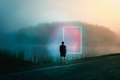 Rear view of man walking on road against sky