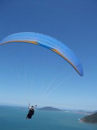 Paraglider flying over islands in sea