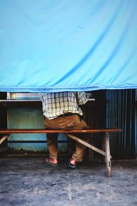 Low section of man standing by built structure