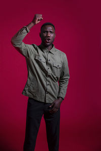 Portrait of young man standing against red background