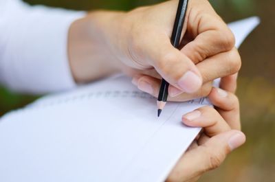 Close-up of person hand writing in book