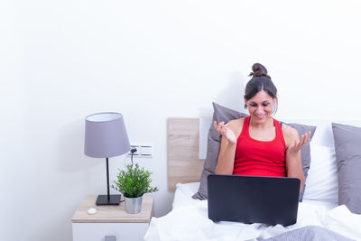 Young woman using mobile phone while sitting against white background