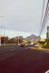 Cars on road against cloudy sky