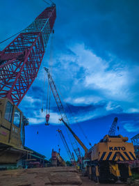 Low angle view of cranes against blue sky