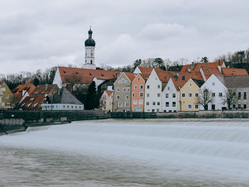 Houses by buildings against sky in city during winter