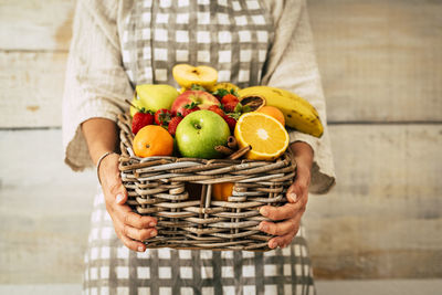Midsection of woman holding fruits in basket