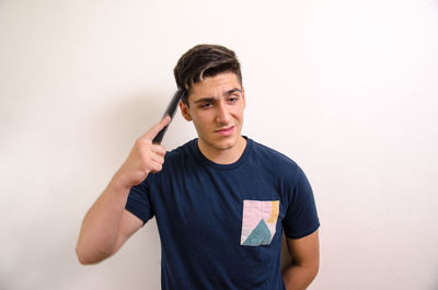 Portrait of young man standing against white background