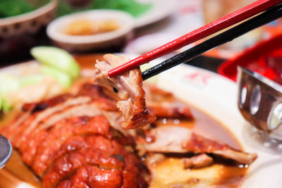 Close-up of chopsticks holding roasted meat