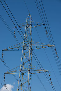 Low angle view of electricity pylon against clear blue sky