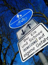 Low angle view of sign board against blue sky