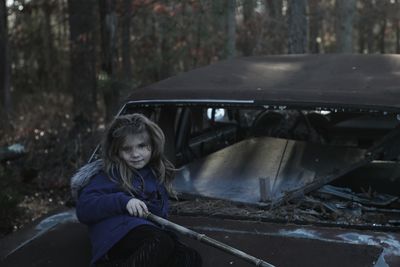 Portrait of girl sitting on abandoned car