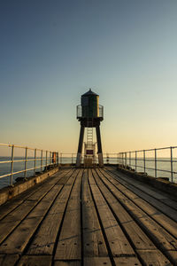 Pier over sea against clear sky during sunset