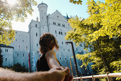 Woman holding hand of man against building