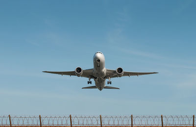 Low angle view of airplane flying against clear blue sky
