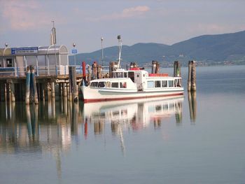 Boats moored at harbor against sky