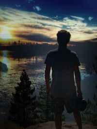 Silhouette man standing by tree against sky during sunset