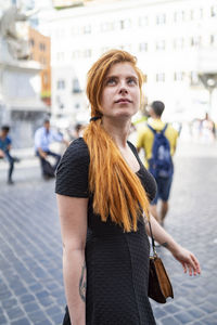 Young ginger woman walking and sightseeing in city