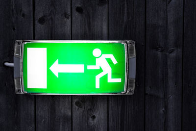 Close-up of illuminated directional sign on wooden door