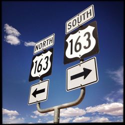 Low angle view of road sign against blue sky