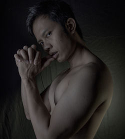 Portrait of young man looking away against black background