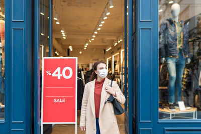 Happy woman wearing mask standing by shopping mall