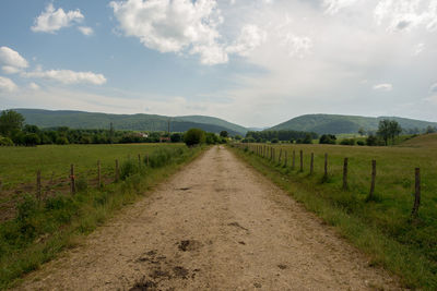 Road amidst field against sky