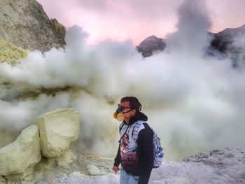 Man wearing gas mask while standing against volcano