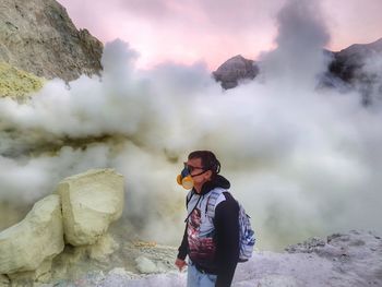 Rear view of man standing on rocks against mountain