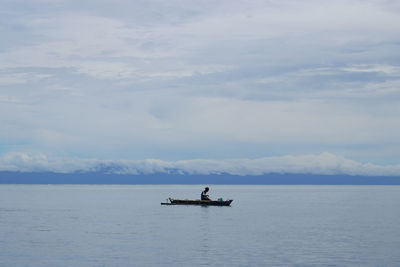 Mid distance view of man on rowboat in sea