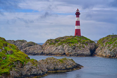 Red and white lighthouse tower amongst the sharp rock 