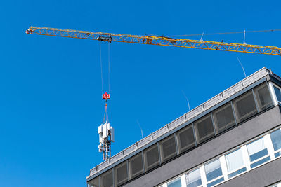 Low angle view of crane against clear blue sky