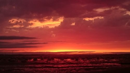 Scenic view of sea against cloudy sky during sunset