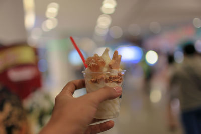 Cropped hand holding ice cream in store