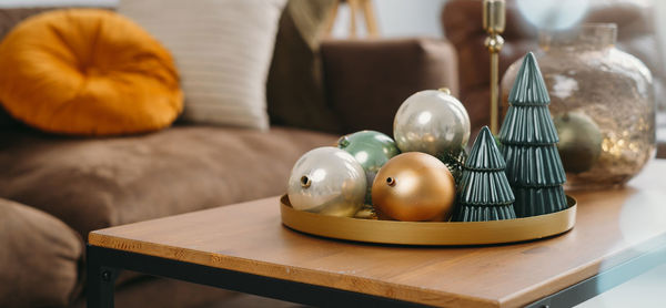 Christmas decor on the table of livingroom. baubles and christmas small toy trees on tray by sofa