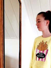 Girl looking at mirror while standing at home